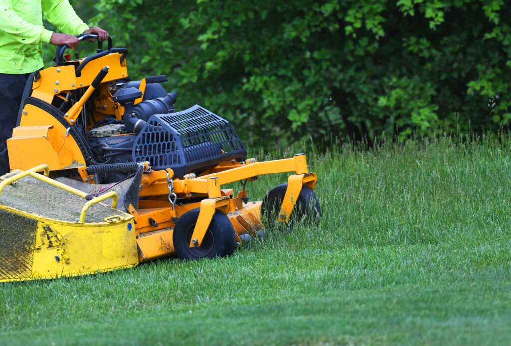 Sugarhouse Vermont employee mowing a lawn with a zero-turn ride-on mower